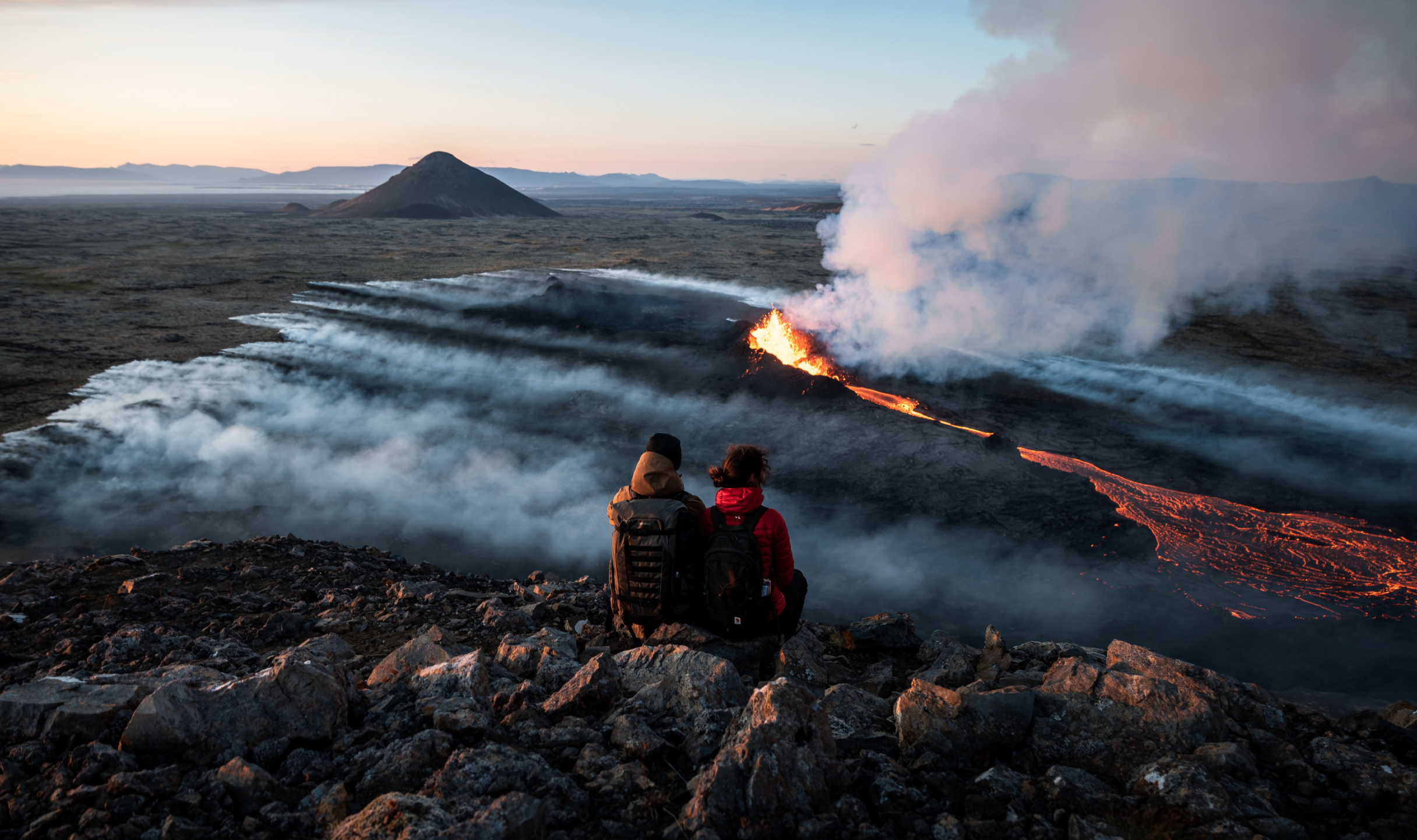 Photo of a couple facing an active volcano in Iceland